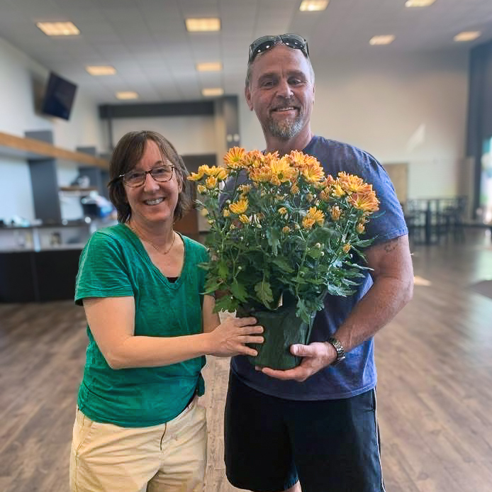 A Boulevard St. Peters team member presents a pot of beautiful yellow flowers to a local business owner.