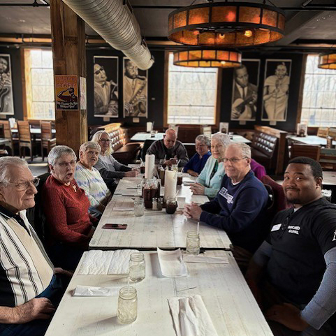 Seniors and team members from Boulevard St. Peters enjoy a local restaurant decorated with warm lighting and black and white portraits of jazz musicians.