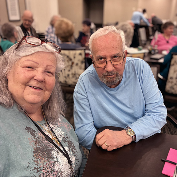 A senior man and woman sit together smiling at Boulevard St. Peters.